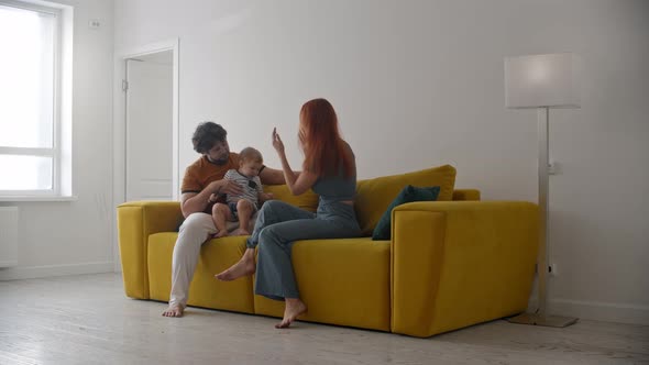 Family Sitting on Yellow Couch and the Baby Holding Two Pencils