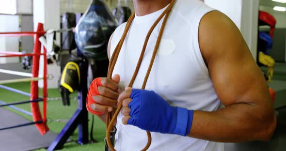 Senior man standing with skipping rope in fitness studio