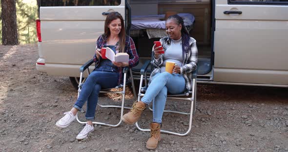 Multiracial women friends having fun camping with camper van