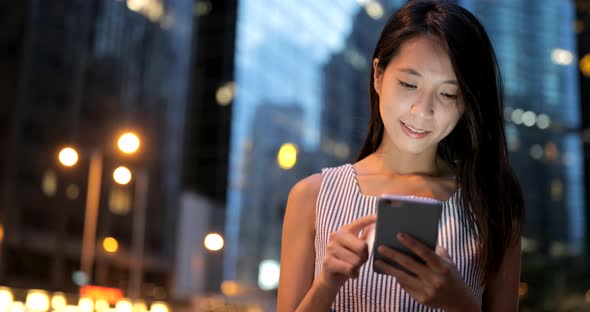 Woman looking at mobile phone in the city of Hong Kong 