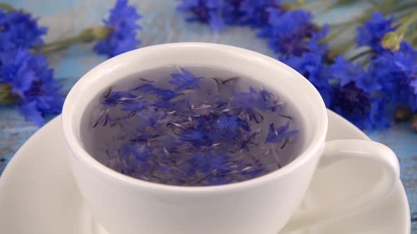 Brewing a tisanes from knapweeds flowers in white cup.