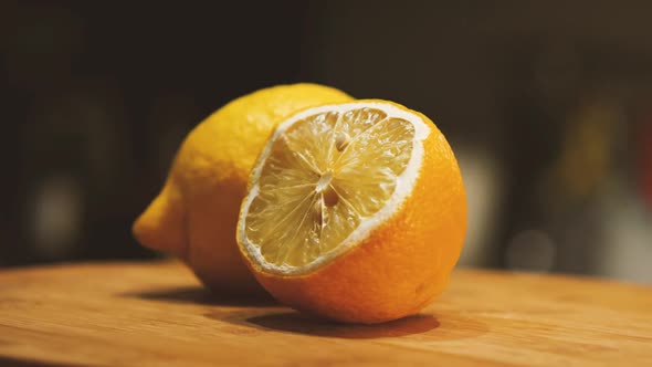 Two lemons lie on a cutting board. One whole and the other cut in half. The camera flies around