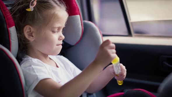 Little Girl Enjoying Blowing Soap Bubbles During Riding Car Seat