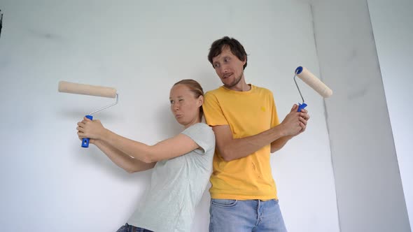 A Happy Man and Woman Paint the Wall Using a Roller Painter