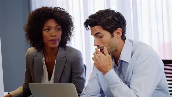 Businessman and businesswoman discussing over laptop