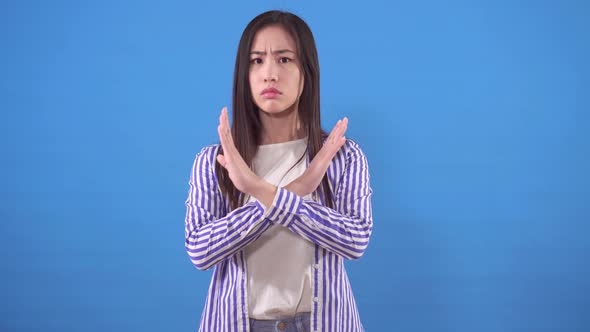 Young Asian Woman with a Negative Gesture Shows No on a Blue Background