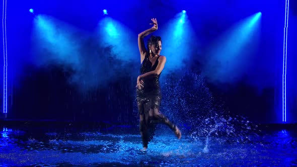 Professional Dancer Dancing Flamenco in a Black Shiny Dress Against the Background of Falling Drops