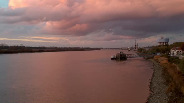 Pan over pink reflecting light off clouds and ships docking station.