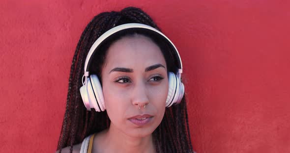 Mixed race girl listening music playlist outdoor with red background