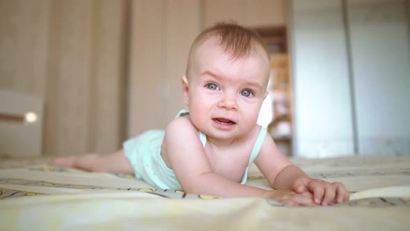 Close Up of a Sad Baby on the Bed. A Toddler Is Going To Cry. Infant Firl in Pajamas. Dissapointed