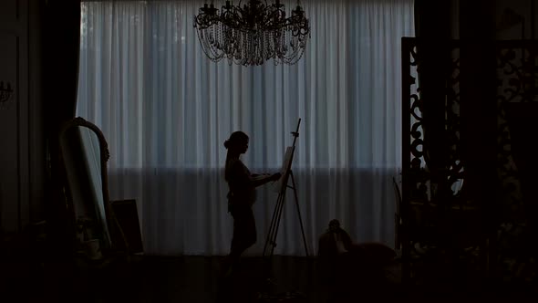 Silhouette of an Artist Who Draws on Canvas in a Drawing Studio.