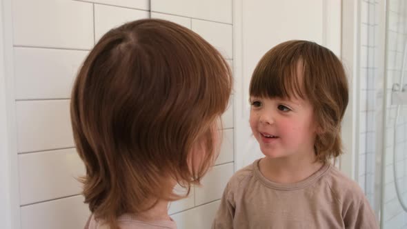 Cute Child Examines Himself in Mirror