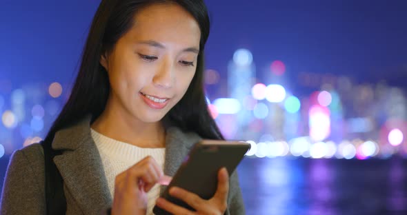 Businesswoman use of mobile phone in Hong Kong at night