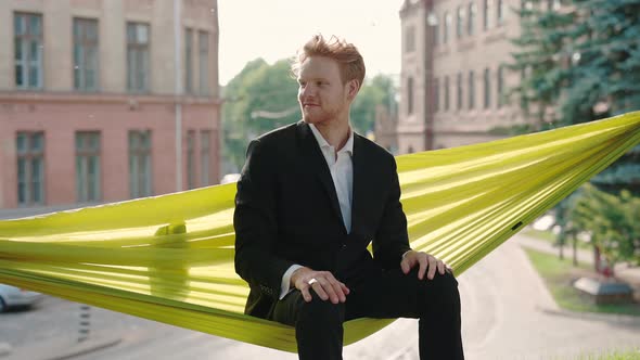 Smiling Redhead Man in Suit Relaxing in Hammock Outdoors