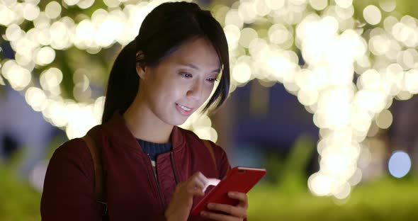 Woman use of mobile phone at night with city bokeh background