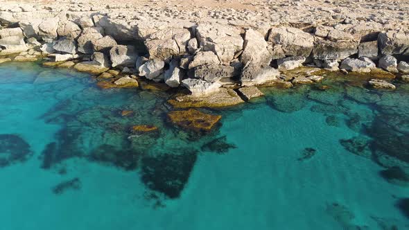 Aerial Top View Footage By Drone of Ocean Blue Water and Rocks A Calm Sea Washes the Rocky Mountain