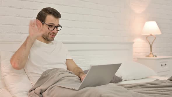 Video Chat on Laptop By Young Man in Bed