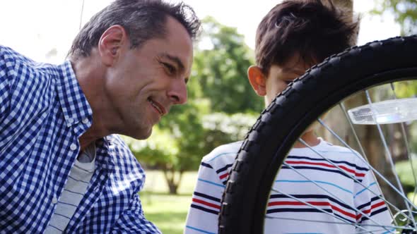 Son and father repairing their bicycle in park