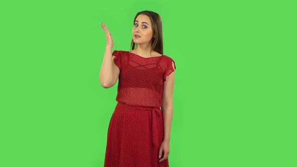 Tender Girl in Red Dress Is Talking and Pointing Side Hand for Something, Copy Space. Green Screen