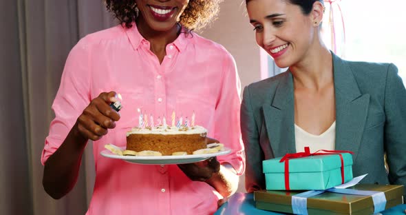 Businesswoman lighting candles on cake with colleague