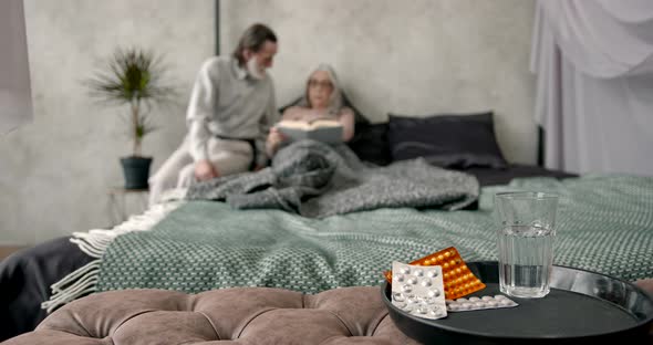 Pills and Glass and Senior Couple on Background