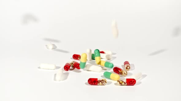 Closeup of Different Medical Pills Falling on Table on White Background