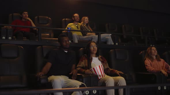 Mixed Raced Young Couple Sitting in Movie Theatre and Watching Film
