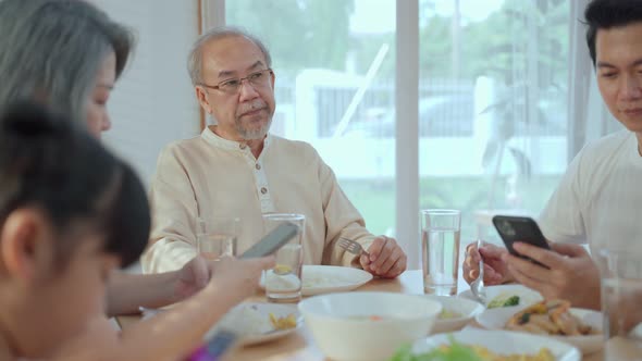 Asian Addicted family using mobile phone while eating breakfast not pay attention to Senior old man.