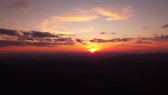 Person Standing on Rock with Epic Mountain Viewpoint with a Sunset Drone Aerial Landscape Shot