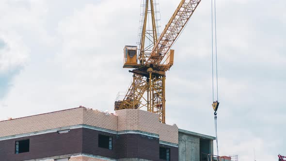 Timelapse footage of a high crane works on building site with a house