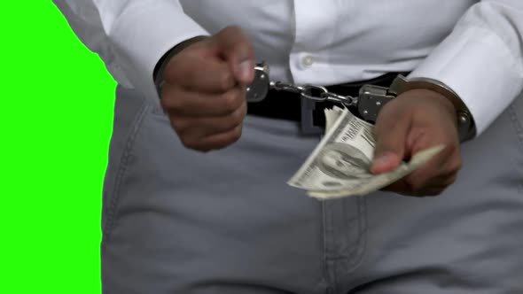 Man in Handcuffs Holding Money on Green Screen.