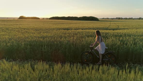 Girl on Bicycle in Green Field Drone Shooting