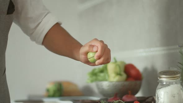 Man is cooking fish with baked vegetables. Male hands with lime. Slow motion