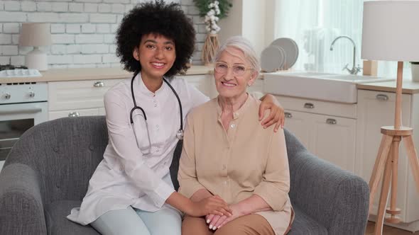 Afro American Woman Doctor and Patient Senior Woman Sitting on Sofa and Smiling