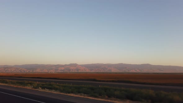 Driving to Los Angeles with mountains in the valley in the distance at sunset