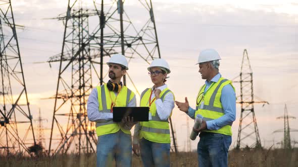 Electric Workers Discuss Work, Standing on Power Grids Background.