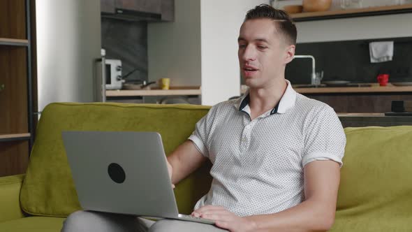 Young Man Using Video Chat on Laptop Computer To Communicate with Friends or Business Partners