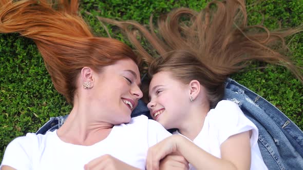 Little girl with mom relaxing in summer city park.