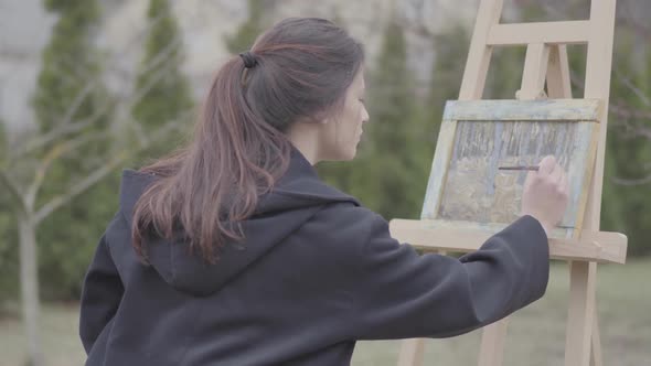 Successful Artist Paints on the Canvas in the Backyard. Beautiful Enthusiastic Girl Engaged in