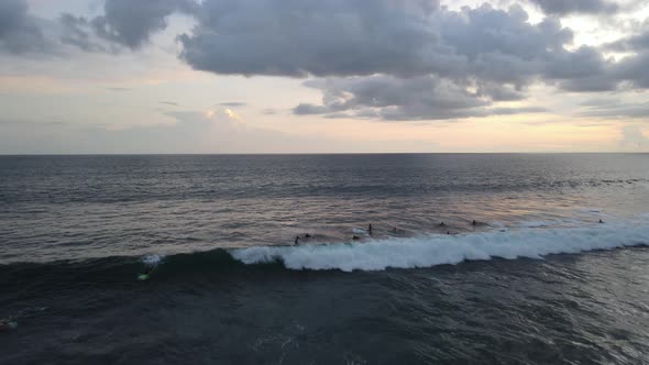 Aerial view of people surfing on waves during sunset when vacation in Bali, Indonesia.