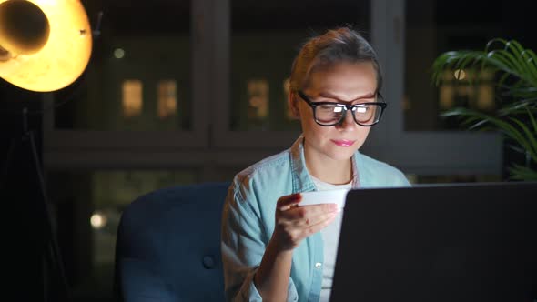 Woman is Sitting in the Armchair and Makes an Online Purchase Using a Credit Card and Laptop at