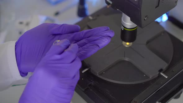 Scientist in a Laboratory Uses a Microscope. He Investigates Drugs or Powders