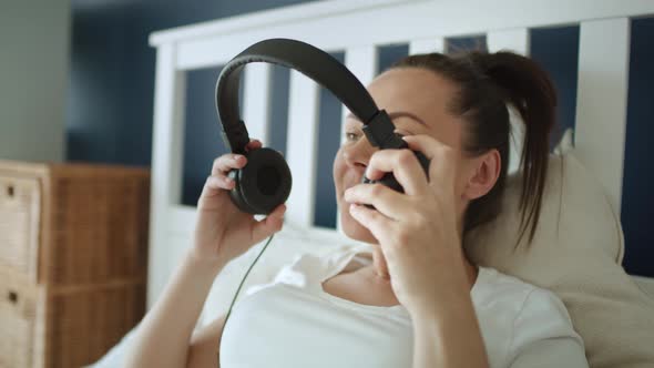 Tracking video of pregnant woman putting headphones on pregnant abdomen