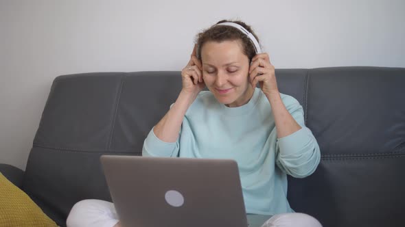 Young Caucasian Woman Puts Her Earphones to Video Call