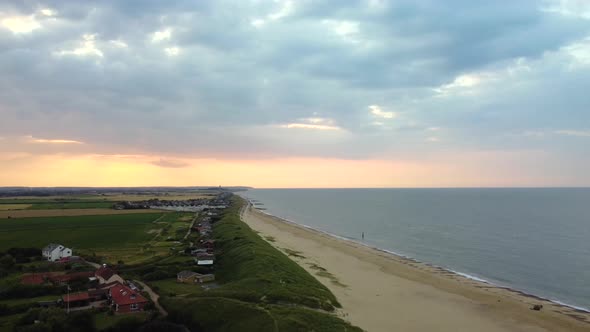 Aerial - Flying backwards over an empty beach in Norfolk at sunset, England