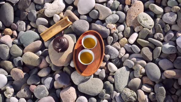 Close-up of two poured cups of tea on a wooden tray, brown teapot,