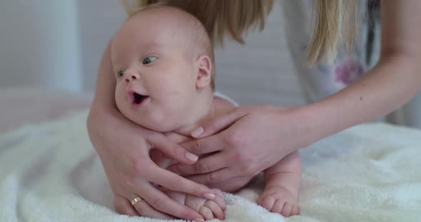 Mother Massaging Happy Baby Boy on Bed