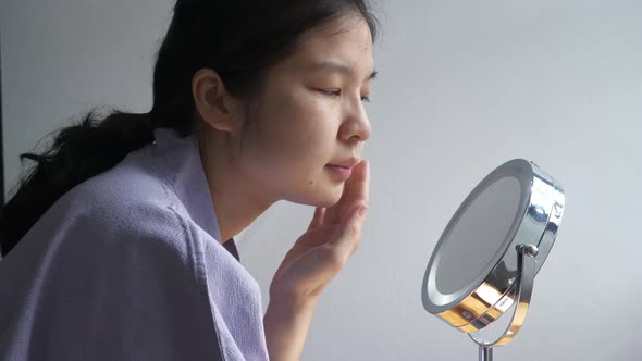 Side view of Asian woman checking facial skin condition