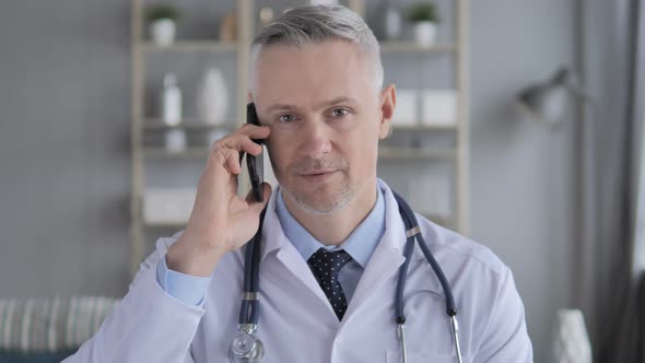 Senior Doctor Discussing with Patient During Phone Talk