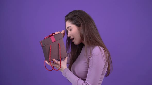 The Curious Young Woman Opens the Gift and Looks Shocked Displaying a Wide Smile